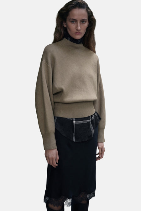 Vrouw met beige trui, zwarte rok met kant.