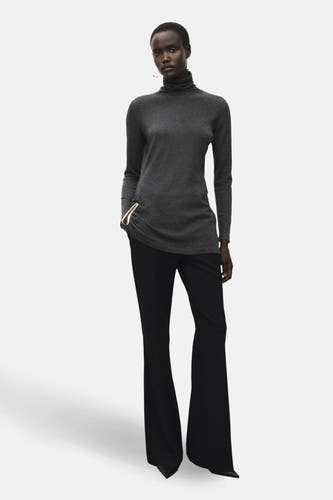 Grijze trui met ronde hals van MANGO, gecombineerd met zwarte broek met wijde pijpen en elegante sieraden.