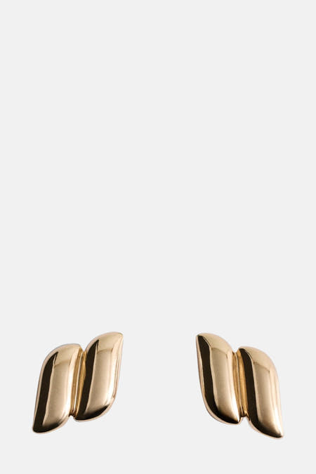 Gouden oorringen van MANGO, met een gebogen, sculpturaal ontwerp.
