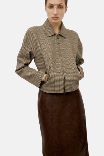 Multikleurige blazer van MANGO met een ruitpatroon, gecombineerd met een bruine leren rok en gouden bril.