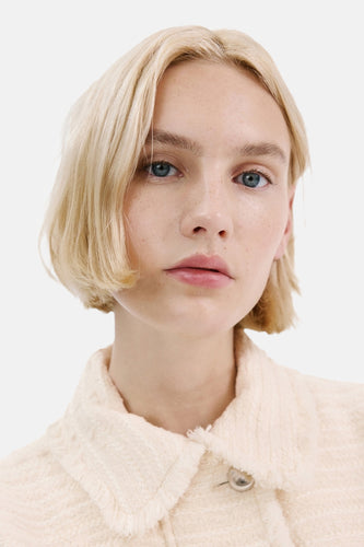 Portret van een vrouw met een beige jasje.
