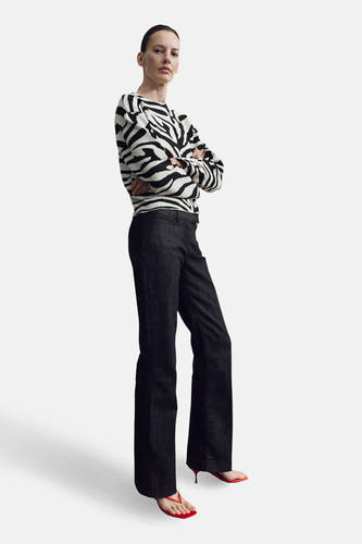 Pull multicolore à col rond de MANGO, avec imprimé zèbre et manches longues, combiné avec un jean foncé et des pantoufles rouges.