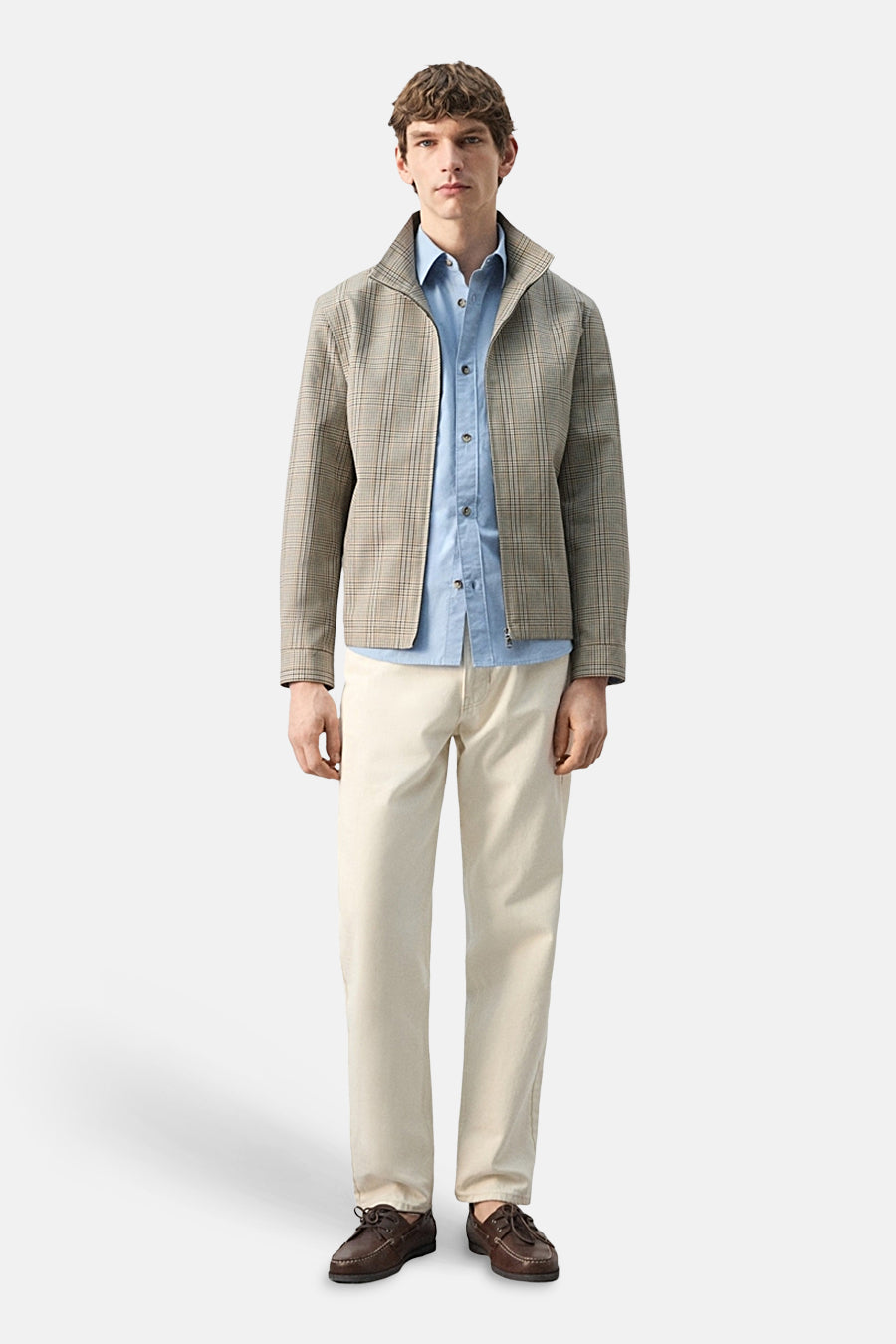 Korte multicolor jas van MANGO, gedragen met een lichtblauw overhemd en beige broek.