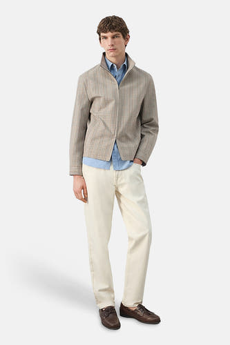 Korte multicolor jas van MANGO, met een ruitpatroon en een ritssluiting, gecombineerd met een blauw overhemd en beige broek.
