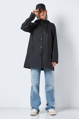 Zwarte regenjas van DROPLETS, met capuchon en gedragen met blauwe jeans en sneakers.