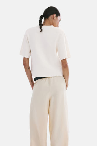 Ecru trui met ronde hals van MANGO, gezien vanaf de achterkant, gecombineerd met crèmekleurige broek.
