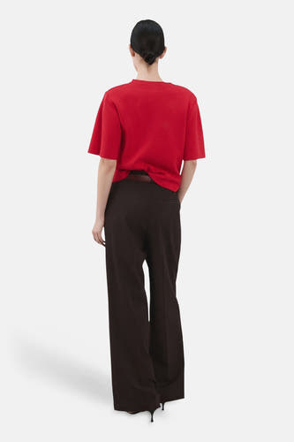 Rode trui met ronde hals van MANGO, gezien van achteren, gecombineerd met donkere broek en hakken.