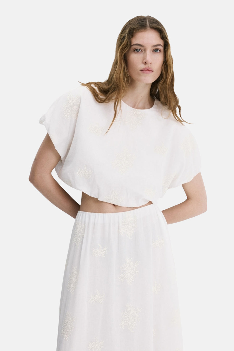 Blouse écru à manches courtes de MANGO, avec détails brodés et dos ouvert.
