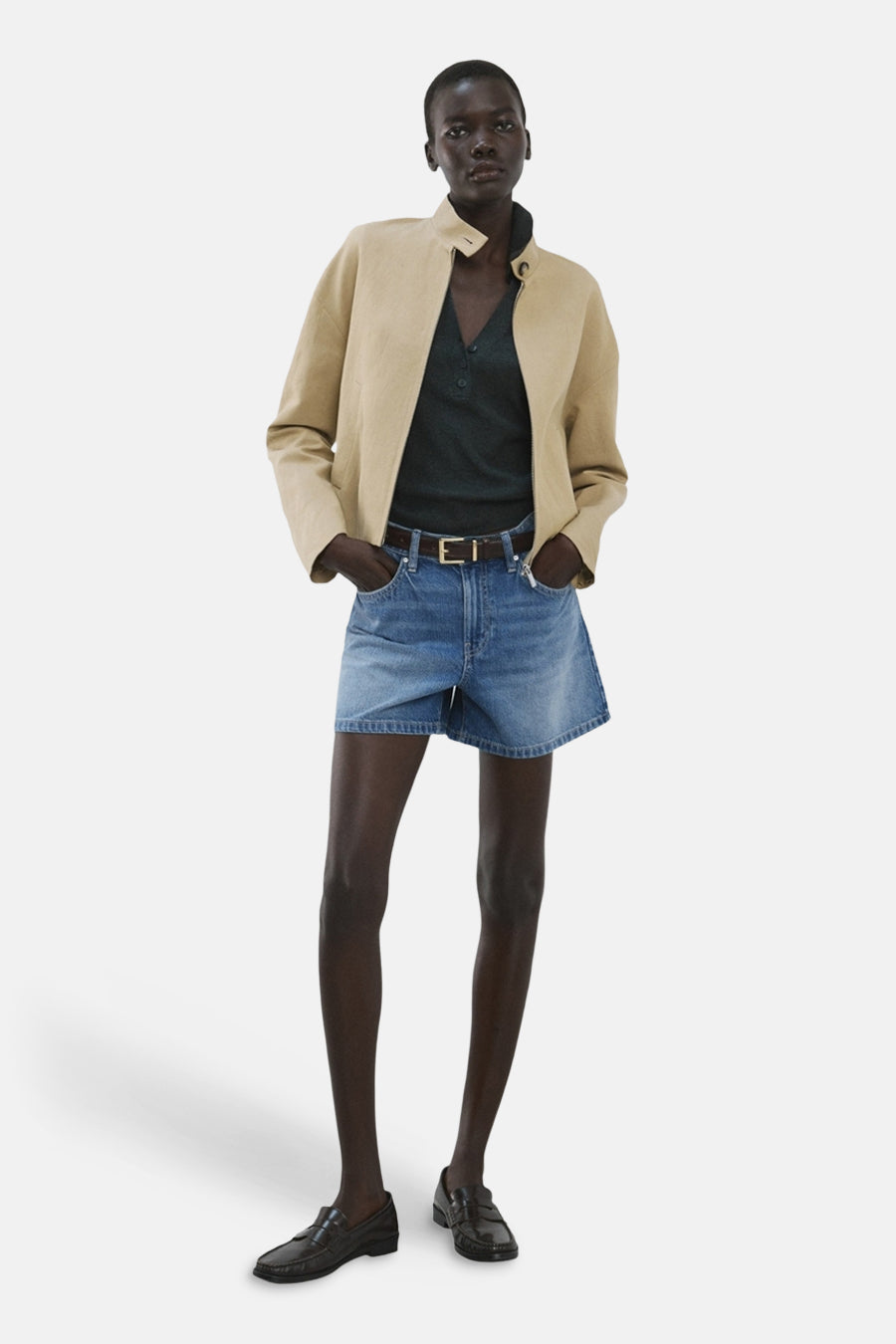 Bermuda short en jean bleu moyen de MANGO, combiné avec une veste beige et des mocassins noirs.