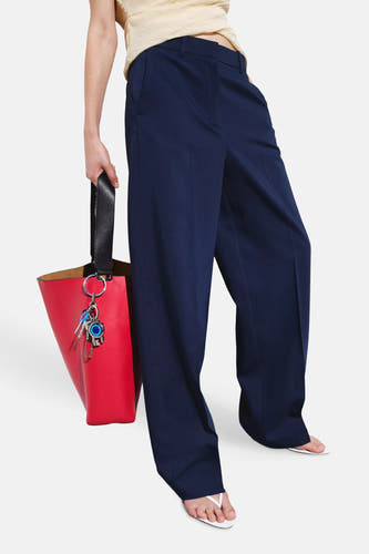 Blauwe kostuumbroeken van MANGO, met wijde pijpen, gedragen met een beige top, rode tas en witte teenslippers.