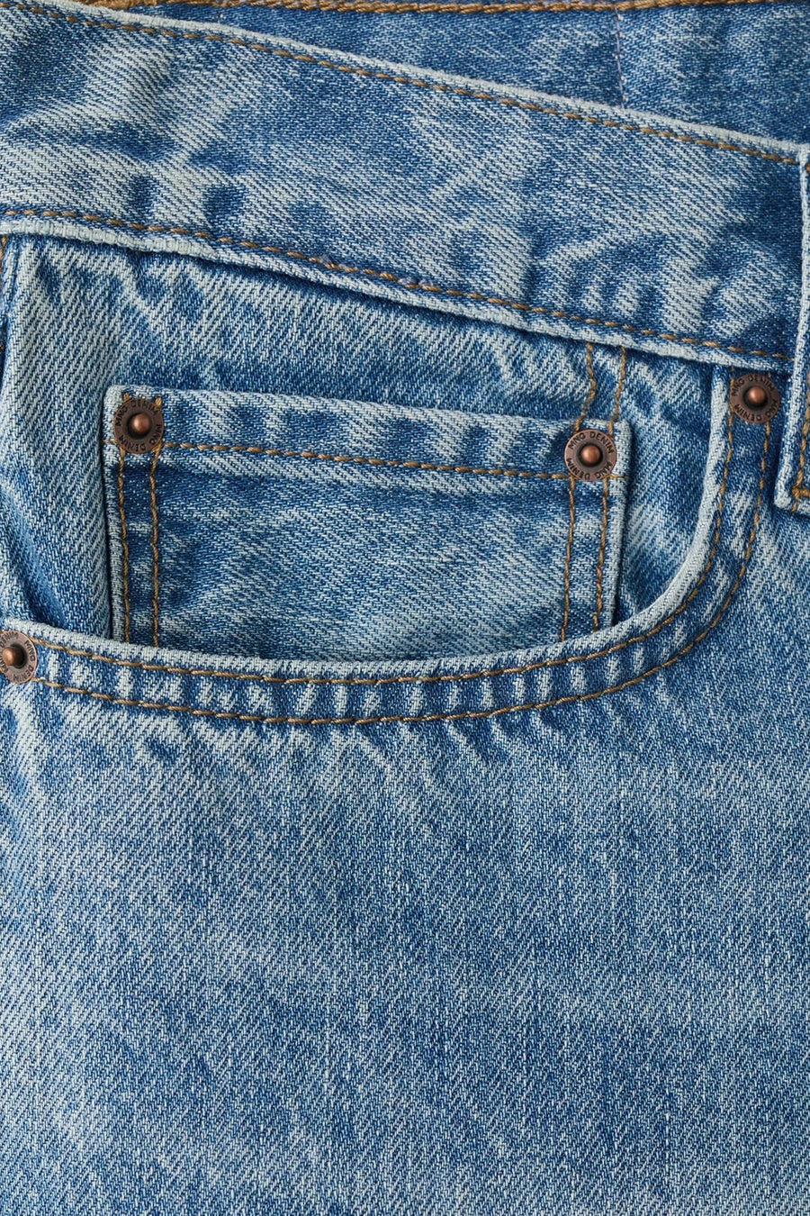 Mid-blauwe denim bermuda van MANGO, close-up van de voorzak met bronskleurige klinknagels en stiksels.