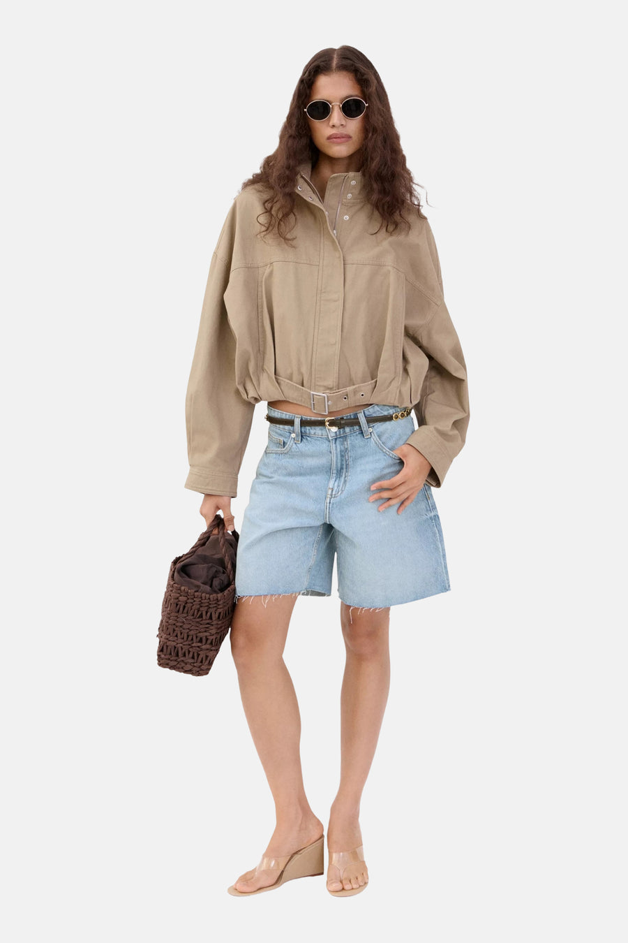 Lichtblauwe spijkerbermuda van MANGO met wijde pijpen en rafelige zoom, gedragen met een beige jasje en heldere sandalen.
