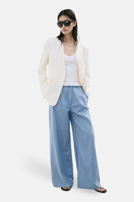 Lichtblauwe denimbroek van MANGO, wijde pasvorm, gestyled met witte blouse en crèmekleurige jas, front view