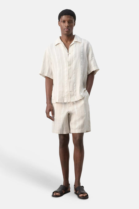 Beige gestreepte bermuda van MANGO met verticale strepen, gedragen met een bijpassend overhemd en sandalen.