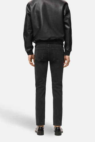 Jean slim fit en denim gris foncé de MANGO, vu de l'arrière, associé à une veste en cuir noir et des chaussures noires.
