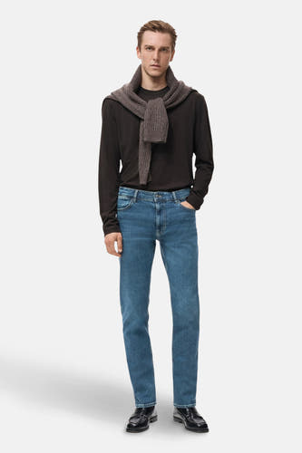 Boutons de jeans en denim bleu foncé de MANGO, stylés avec une chemise brune et un gilet brun foncé autour du cou.
