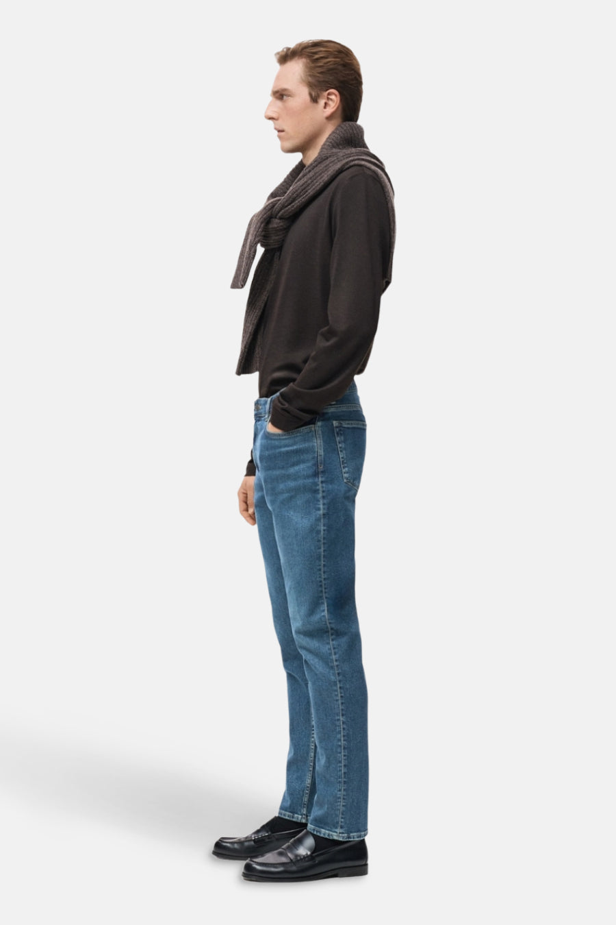 Jean tapered en denim bleu marine de MANGO, porté avec une chemise marron et des loafers, en vue latérale.