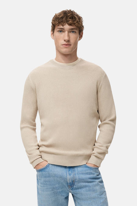 Beige trui met ronde hals van MANGO, met een fijn ribpatroon en lange mouwen, gecombineerd met een spijkerbroek.
