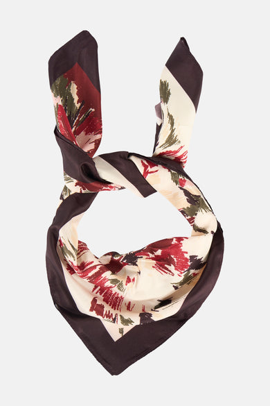 Multikleurige zomersjaal van MANGO, met abstract bloemmotief en bruine randen, geknoopt in een lus.

