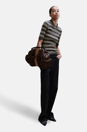 Pull gris à col rond de MANGO, à rayures horizontales, porté avec un jean foncé ample et des chaussures pointues.