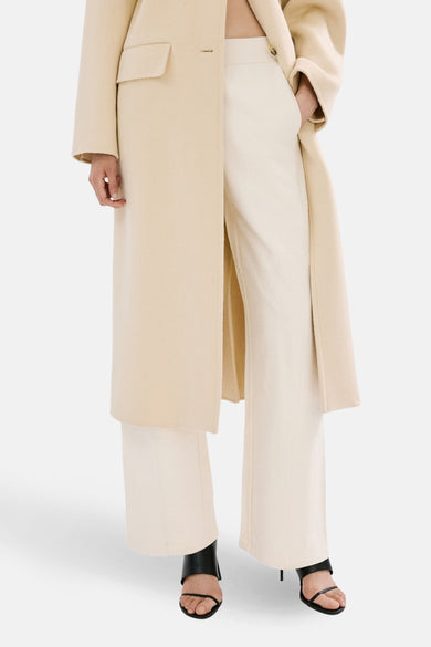 Pantalon de jogging beige de MANGO, vu de dos avec jambes larges et porté avec des talons noirs.