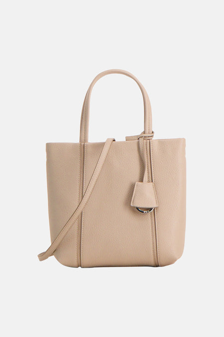 Ecru handtas van MANGO, met korte handgreep en lange schouderband, en een decoratieve hanger met zilveren ring.
