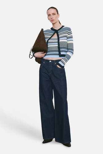 Multikleurig gilet van MANGO, gedragen met een gestreepte cardigan en wijde jeans.
