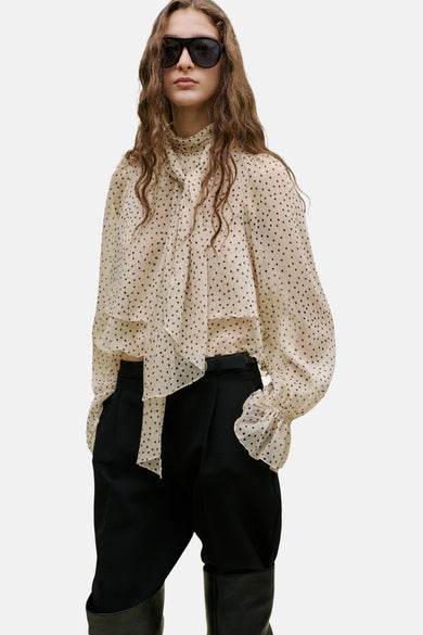 Chemisier beige de MANGO à motif à pois, manches longues à volants et détail de nœud au col, de profil.
