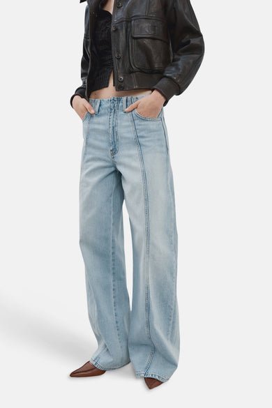 Lichtblauwe wijde jeans van MANGO, met stikseldetails en bruine puntschoenen.
