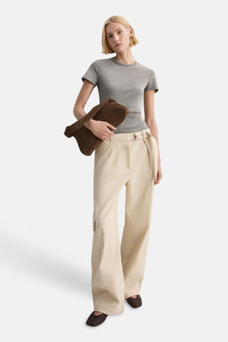 Haut grise de MANGO, portée avec un pantalon crème avec ceinture et un sac et des chaussures marron.