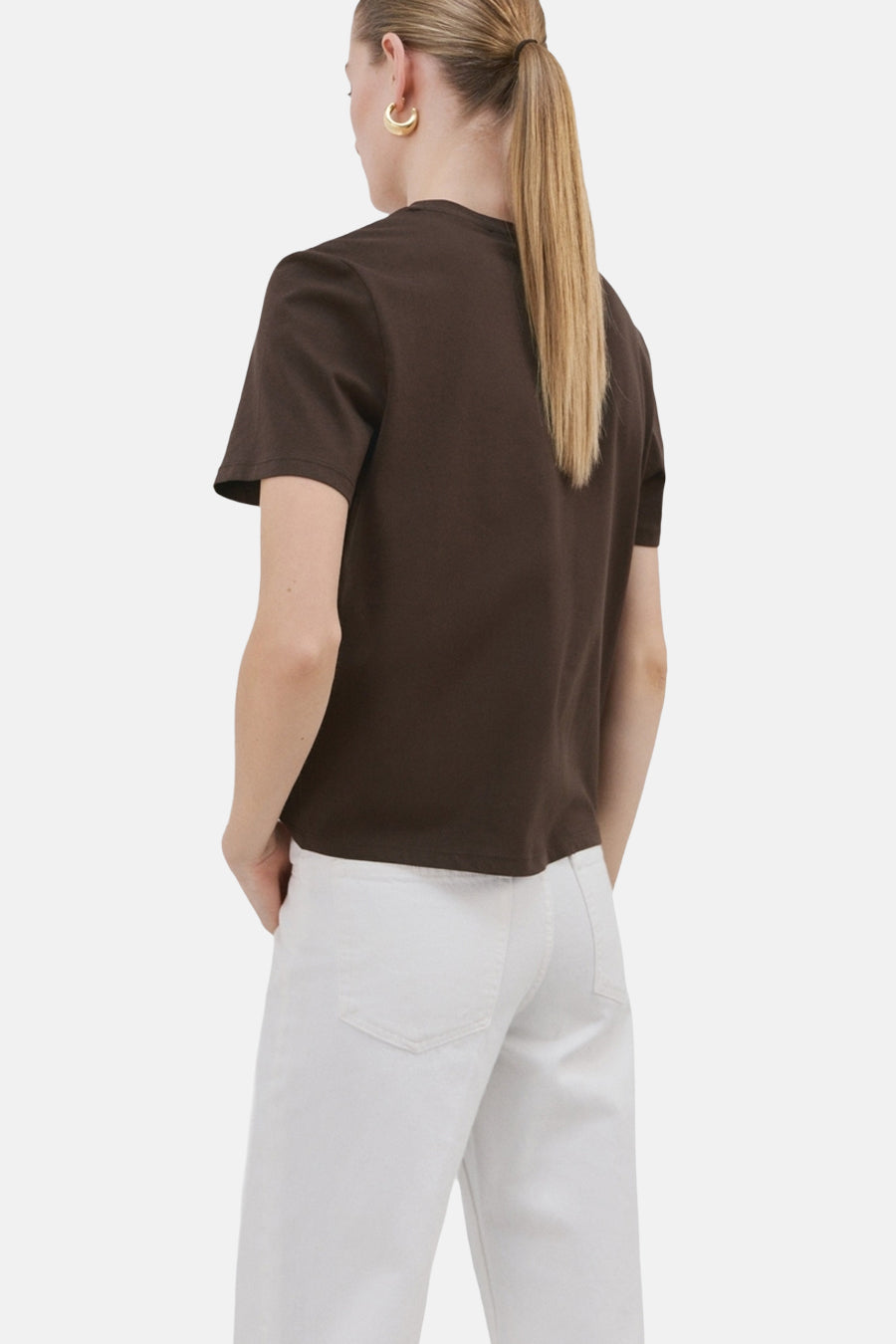 Bruin T-shirt van MANGO, gezien van achteren, met witte broek en gouden oorbellen.