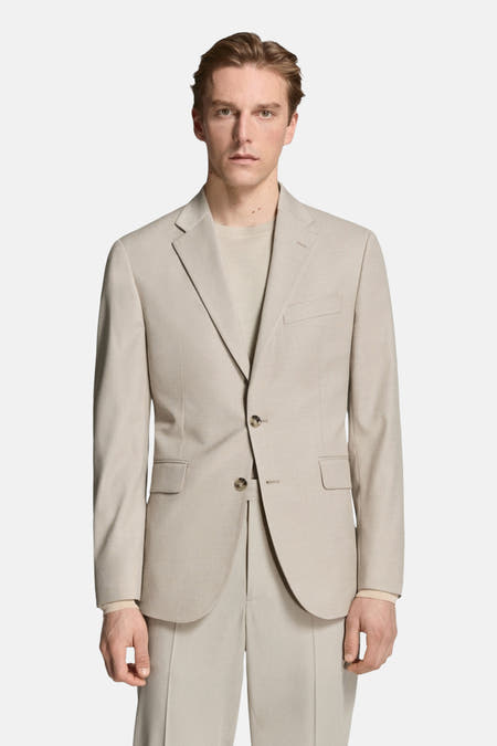 Beige blazer van MANGO, met twee knopen en zakken, gedragen over een beige T-shirt en broek.