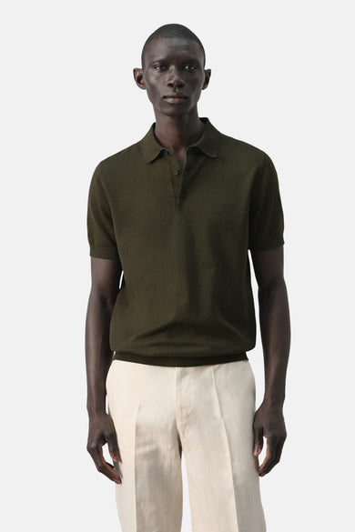 Groene polo van MANGO, met korte mouwen en een klassieke kraag, gedragen met een crèmekleurige broek.
