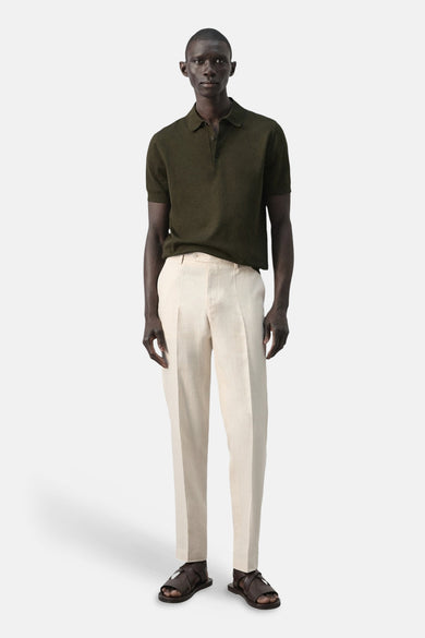 Groene polo van MANGO, gedragen met crèmekleurige linnen pantalon en bruine sandalen.