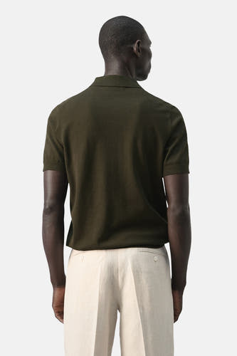 Groene polo van MANGO, gezien van achteren, gecombineerd met een lichte pantalon.
