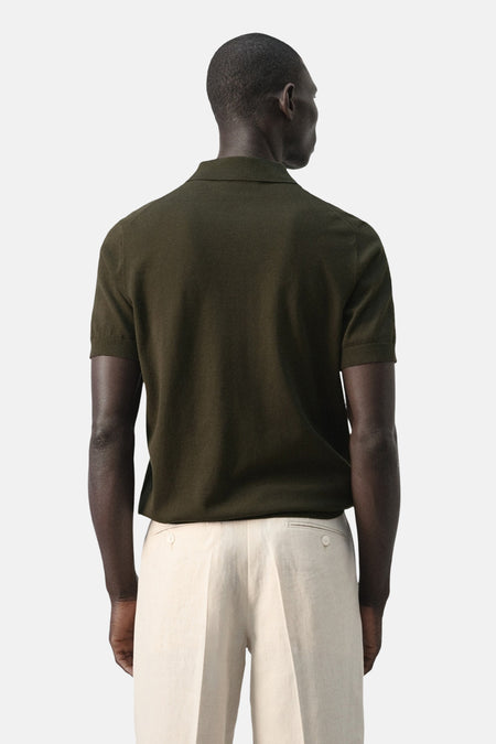 Groene polo van MANGO, gezien van achteren, gecombineerd met een lichte pantalon.

