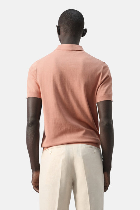 Oranje polo van MANGO, achteraanzicht, gecombineerd met een lichte pantalon.