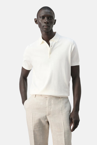 Polo blanche de MANGO, vue de dos, portée avec un pantalon en lin.