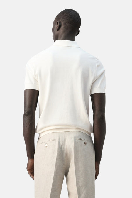 Witte polo van MANGO, gezien van achteren, gedragen met linnen broek.