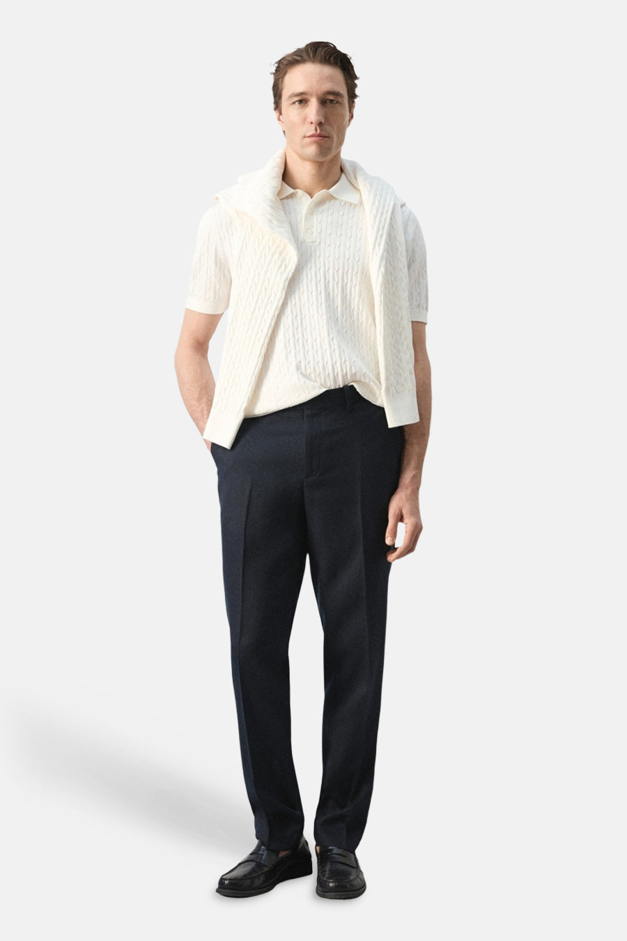 Witte polo van MANGO met kabelpatroon en korte mouwen, gedragen met een trui over de schouders en donkere pantalon.

