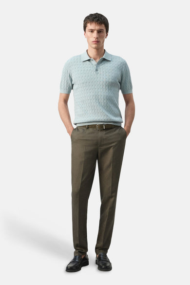 Polo bleu de MANGO, à manches courtes et avec un subtil motif torsadé. Un pantalon foncé et des mocassins noirs complètent la tenue.