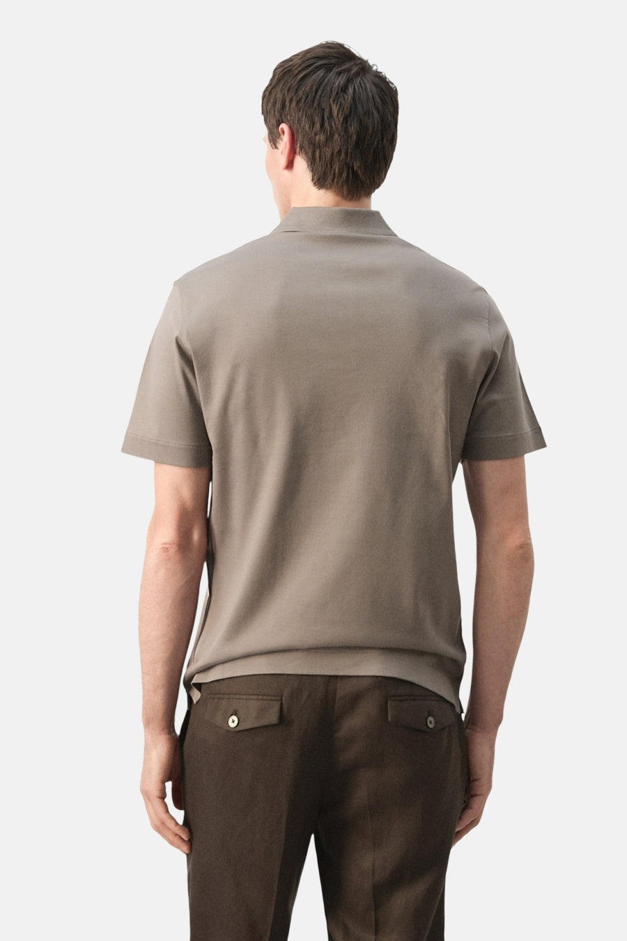 Bruine polo van MANGO, gezien van achteren, gecombineerd met een donkere broek.
