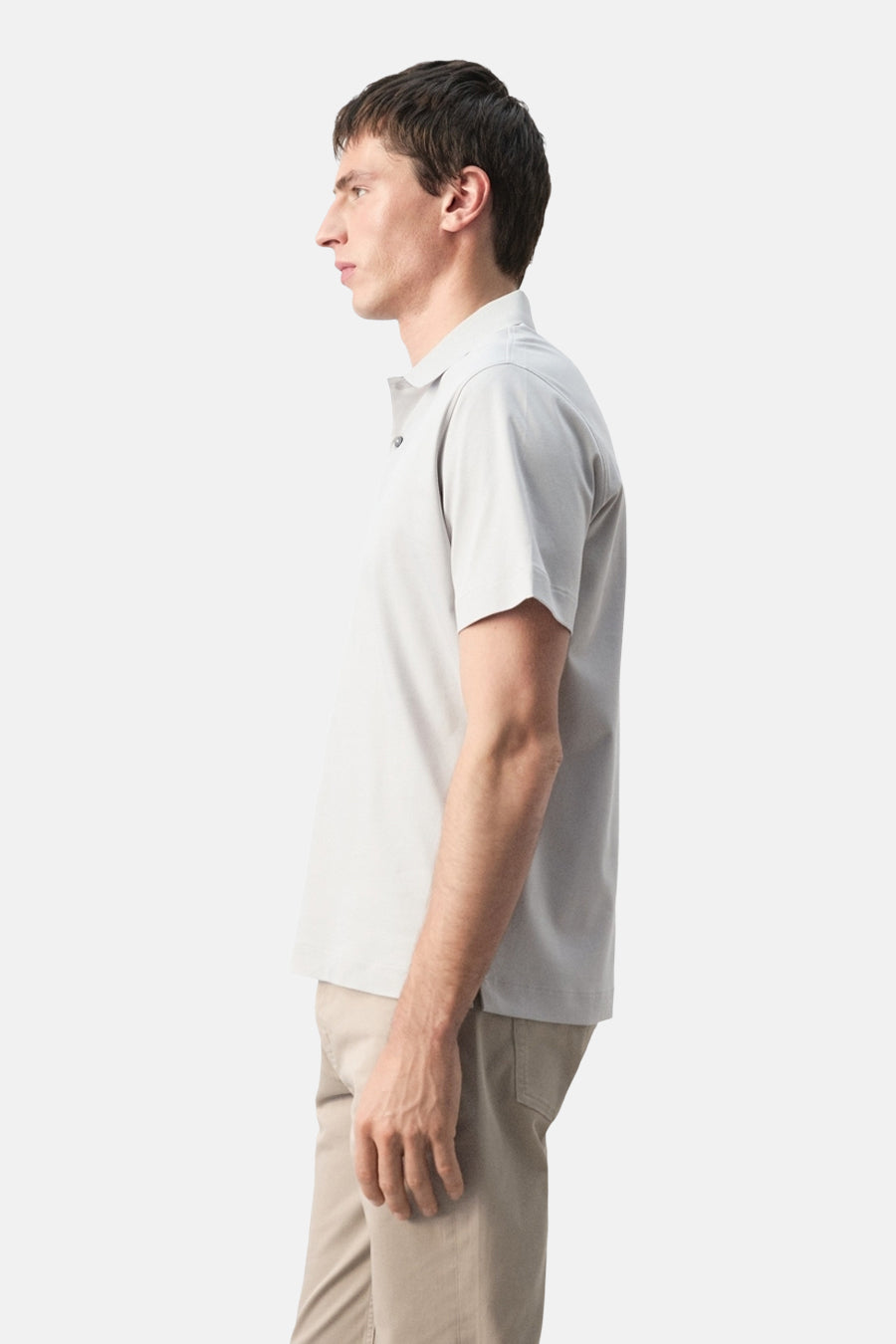 Grijze polo van MANGO, in zijaanzicht gedragen met een beige broek.