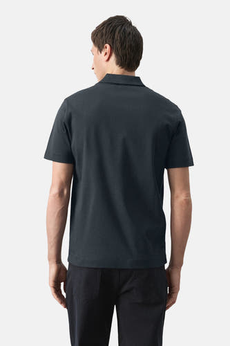 Blauwe polo van MANGO, met korte mouwen, gezien van achteren en gecombineerd met een zwarte broek.

