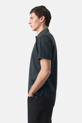Blauw poloshirt van MANGO, in zijaanzicht gedragen met een donkere broek.
