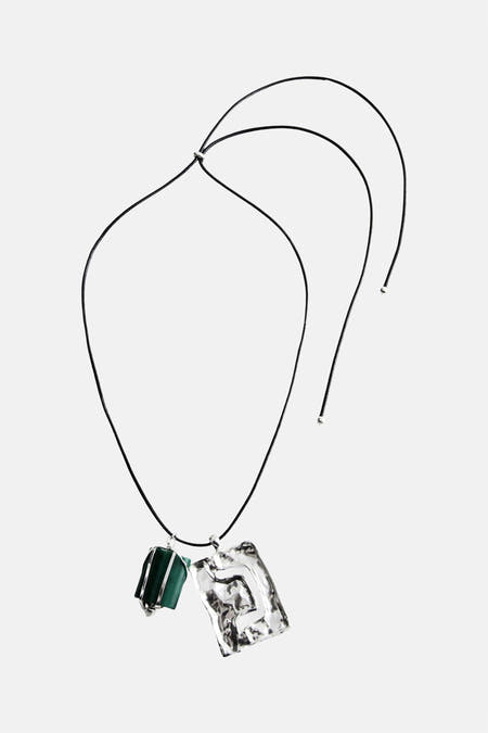 Korte halsketting multicolor van MANGO met een groene steen en een zilverkleurige hanger aan een zwarte koord.
