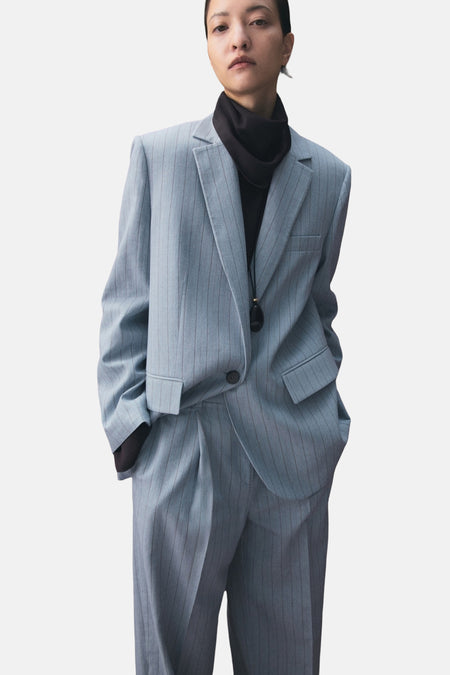 Blauwe blazer van MANGO met krijtstreep en enkele knoop, gecombineerd met een zwarte coltrui en ketting.