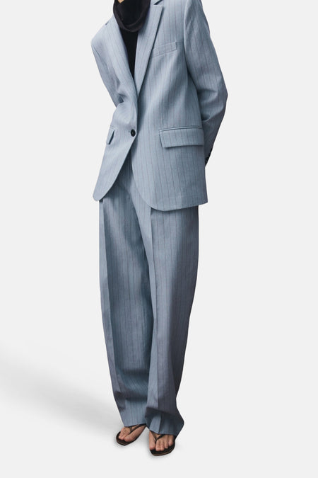 Blauwe blazer van MANGO met krijtstreep en zakken, gedragen met bijpassende broek en sandalen.