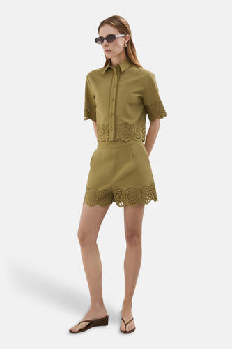 Blouse courte kaki de MANGO avec broderie ajourée circulaire et ourlets festonnés, portée en ensemble.