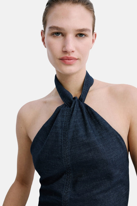 Donkerblauwe denim top van MANGO met halterneksluiting, knoopdetail en zichtbare stiksels.